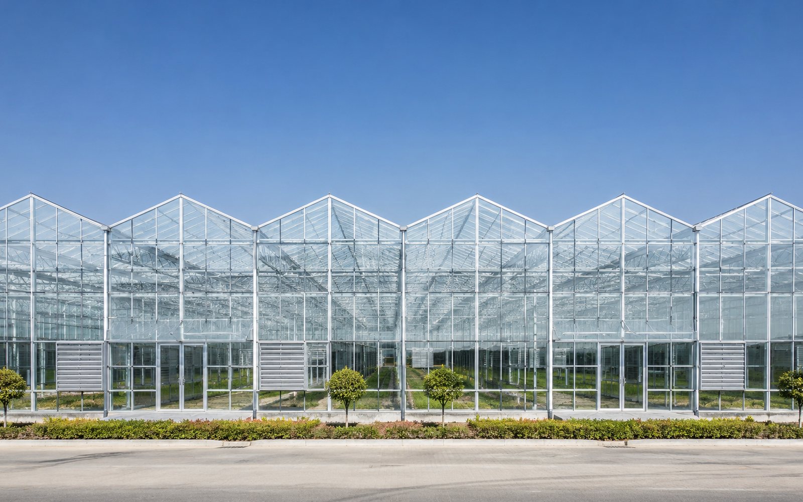Glass greenhouse exterior under a clear blue sky